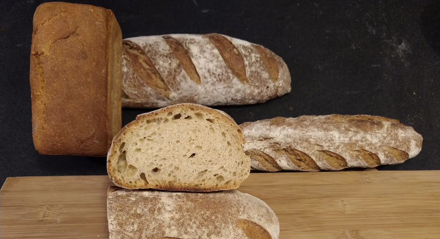 Pain moulé, flûtes et miche au levain tranchée